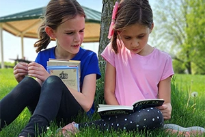 Two kids reading under tree